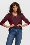 Bordeaux V-hals trui van ONLY, gedragen met middinblauwe jeans en zilveren kettingen.