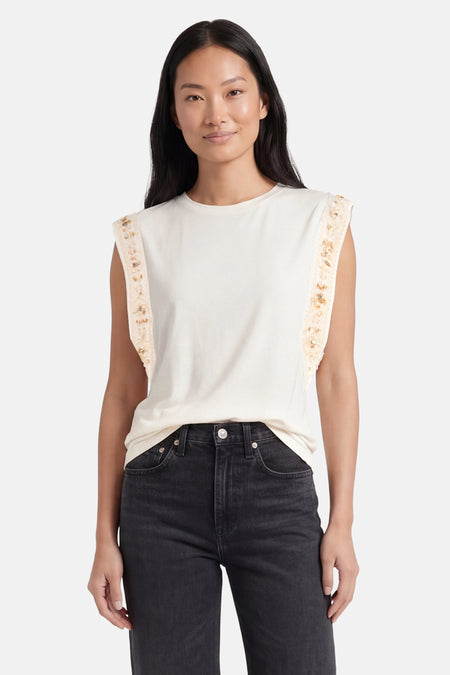 Beige T-shirt met korte mouwen van GOA GOA met gouden paillettenbanden op de schouders, gedragen met een donkere spijkerbroek.