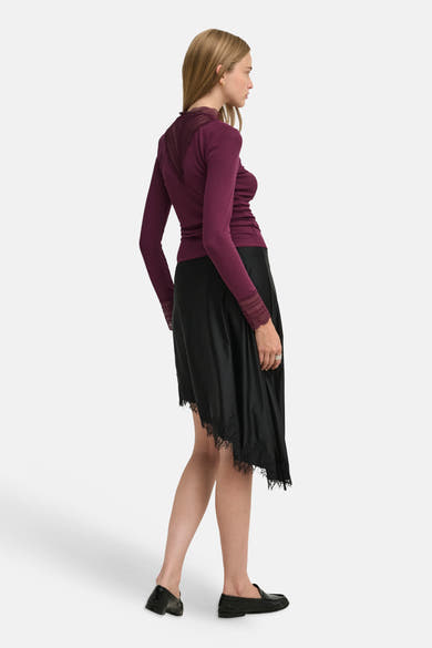 Burgundy long-sleeve t-shirt with lace trim at neckline and cuffs, side view on model wearing black skirt and loafers