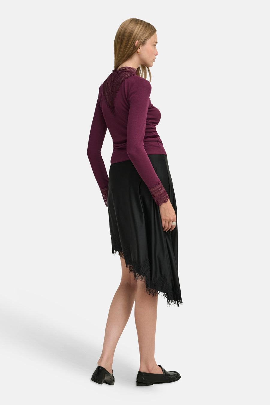 Burgundy long-sleeve t-shirt with lace trim at neckline and cuffs, side view on model wearing black skirt and loafers
