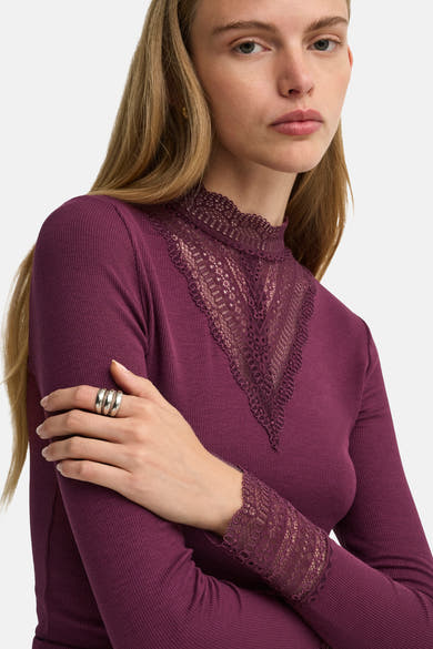 Fig long-sleeve ribbed top with lace V-neck and cuffs, side view on model wearing silver rings