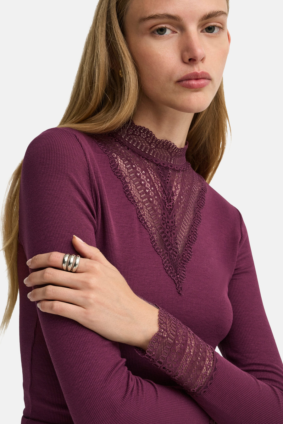 Fig long-sleeve ribbed top with lace V-neck and cuffs, side view on model wearing silver rings