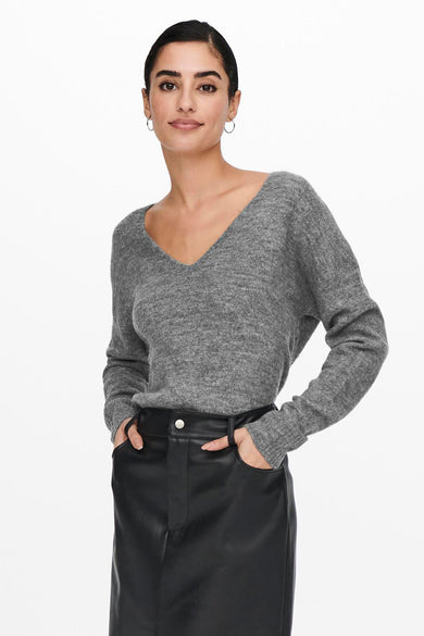 Pull gris à col en V de JDY, porté avec une jupe noire taille haute, mains dans les poches.
