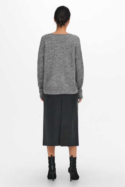 Pull à col rond gris de JDY, porté avec une jupe midi noire et des bottines noires à talons aiguilles.