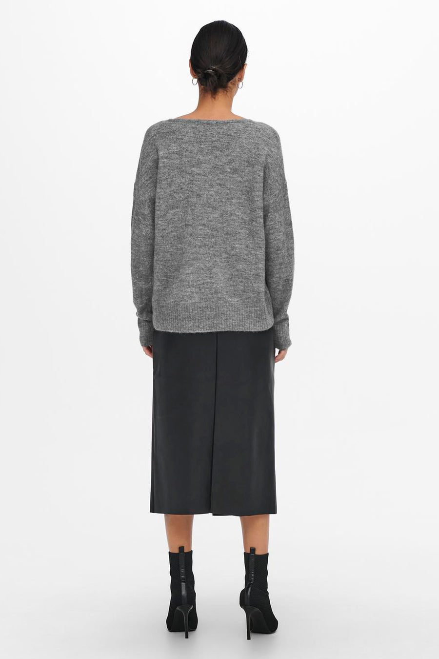 Pull à col rond gris de JDY, porté avec une jupe midi noire et des bottines noires à talons aiguilles.