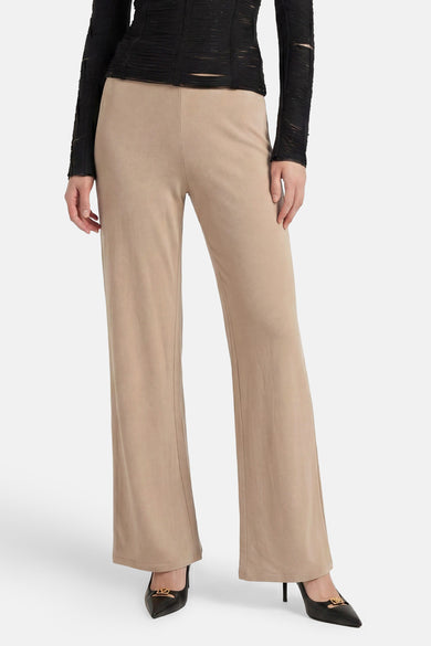 Pantalon de costume beige de GOA GOA, coupe large et fluide, porté avec un haut noir et des escarpins.