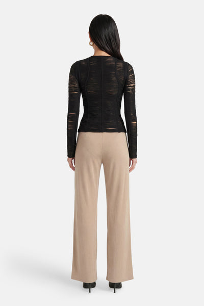 Pantalon de costume beige de GOA GOA, coupe large, porté de dos par une femme avec un haut noir.