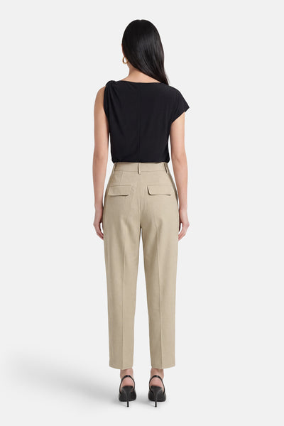 Pantalon de costume beige de GOA GOA, taille haute avec poches à rabat au dos, porté avec un haut noir et des escarpins.