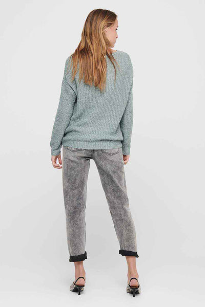 Pull vert de JDY, avec une texture tricotée, porté avec un jean gris et des chaussures à talons.