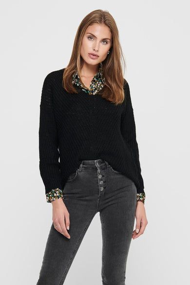 Pull noir à col V par JDY, avec motif floral visible au niveau du col et des poignets.