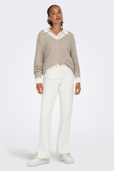 Pull col V brun de JDY porté avec une chemise blanche et un jean blanc à jambes évasées.