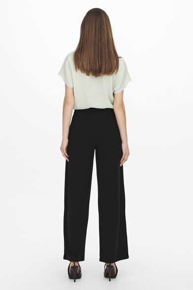 Pantalon de costume noir de JDY, coupe ample, porté avec un haut vert et des chaussures à talons noirs.