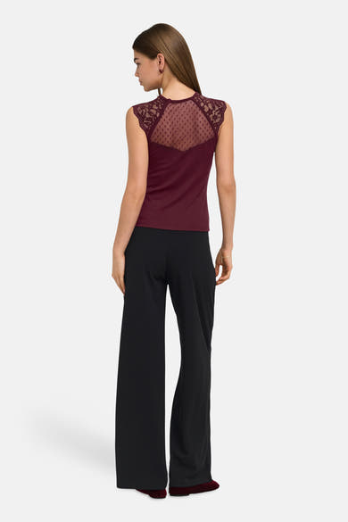 Black wide-leg elastic waist trousers, back view, smooth fabric, worn with burgundy lace-back top and matching shoes