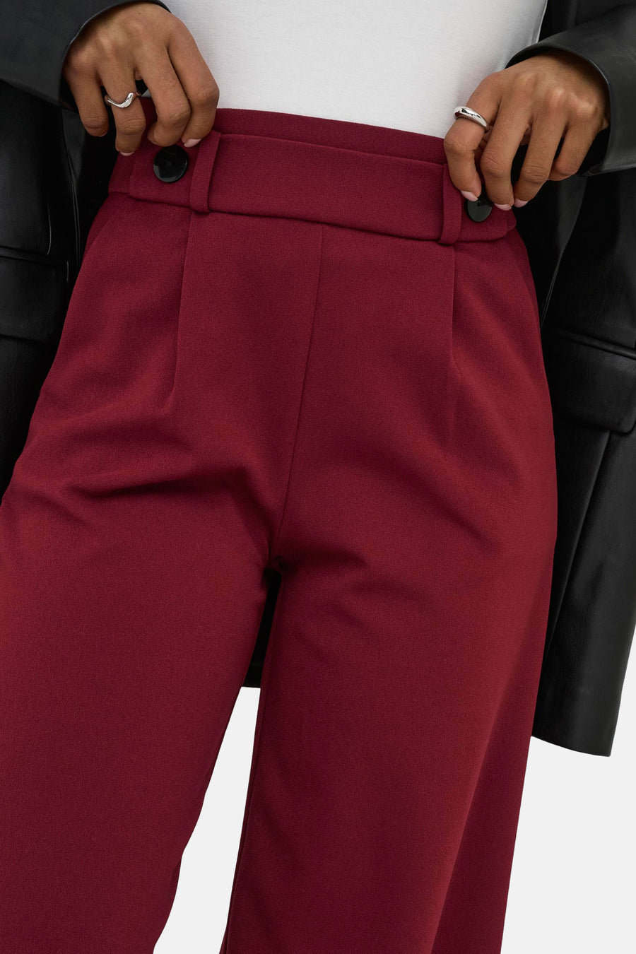 Pantalon de costume rouge de JDY, avec boutons et plis, porté avec une veste noire.
