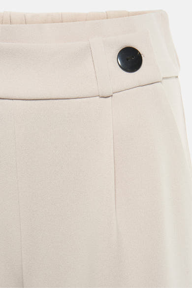 Pantalon de costume beige par JDY, avec fermeture à bouton noir apparent sur la ceinture.

