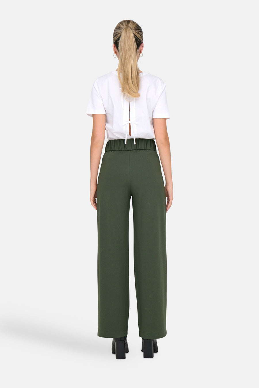 Pantalon de costume kaki de JDY, avec taille élastique et jambes larges, porté avec un t-shirt blanc à dos noué.