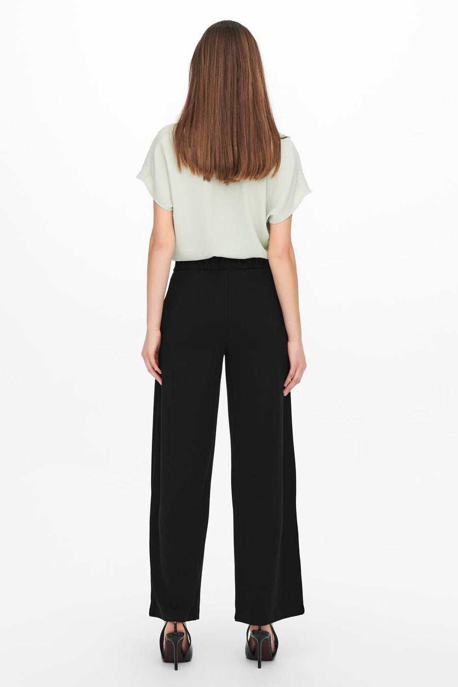Pantalon costume noir de JDY, coupe ample et jambes larges, porté avec un haut vert pâle et des talons noirs.