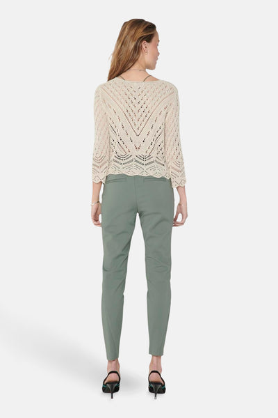 Pull col V beige de JDY, à motifs ajourés, porté avec un pantalon vert olive.
