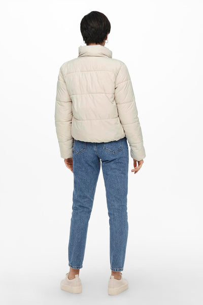 Veste courte écru de JDY, vue de dos, portée avec un jean bleu et des baskets beiges.
