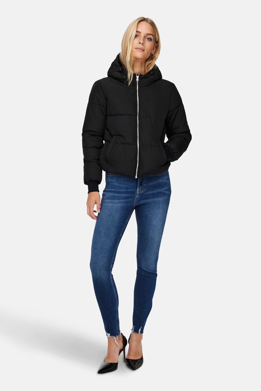 Korte zwarte jas van JDY met zilveren ritssluiting, gedragen met een spijkerbroek en zwarte pumps.