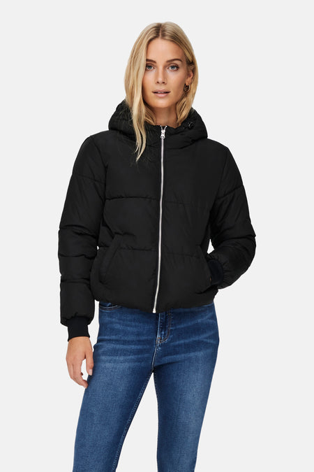 Veste courte noire de JDY, avec capuche, fermeture éclair argentée et portée avec un jean bleu.
