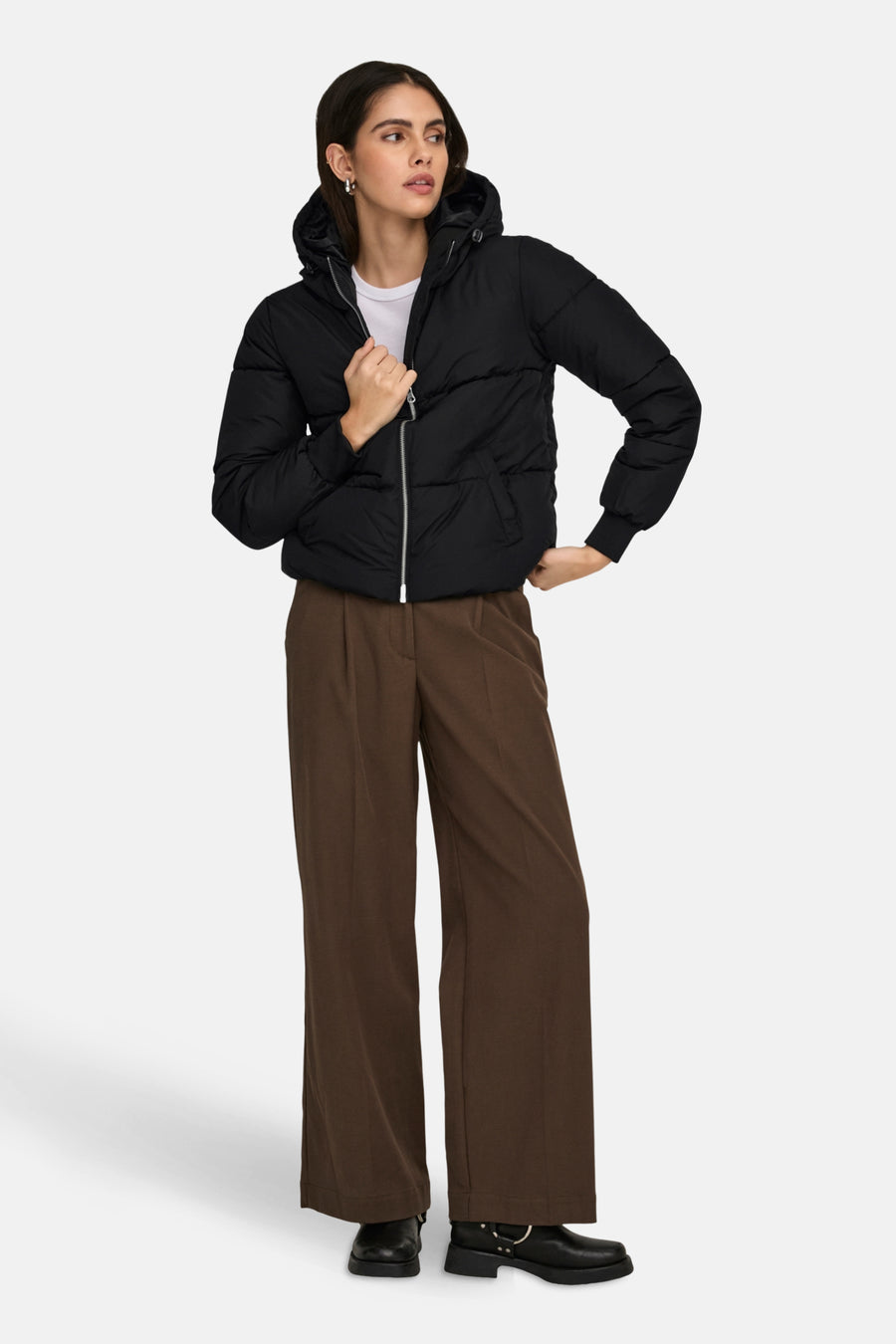 Korte zwarte jas van JDY met capuchon en ritssluiting, gedragen met een bruine broek en zwarte laarzen.