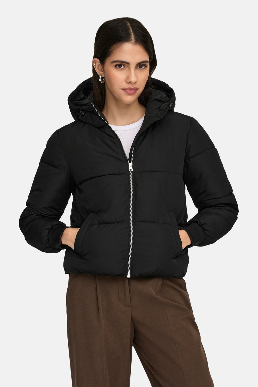 Korte zwarte jas van JDY, met capuchon en zilveren ritssluiting, gedragen met een bruine broek.