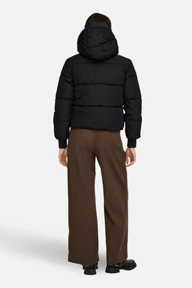 Veste courte noire de JDY, avec une capuche, portée avec un pantalon marron ample et des chaussures noires.