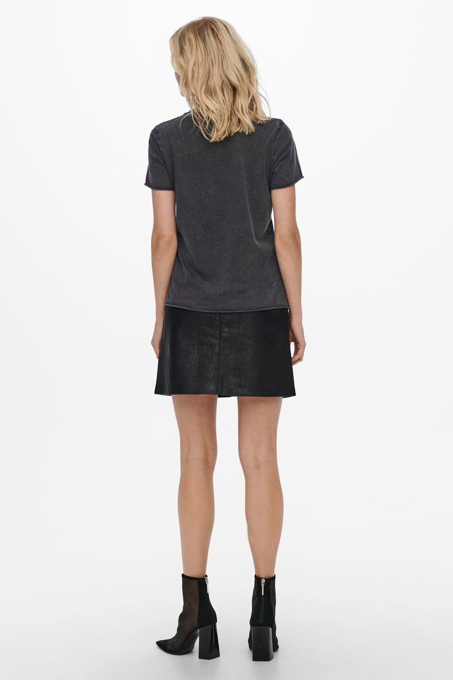 Zwart T-shirt met korte mouwen van ONLY, gedragen met een zwarte rok en zwarte enkellaarsjes met hak.