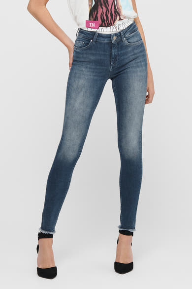 Skinny jeans in donkerblauw denim van ONLY, gedragen met een wit T-shirt en zwarte hoge hakken.