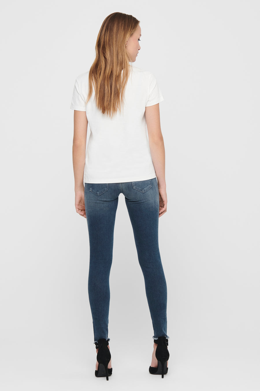 Jean skinny en denim bleu foncé de ONLY, porté avec un t-shirt blanc et des talons hauts noirs.
