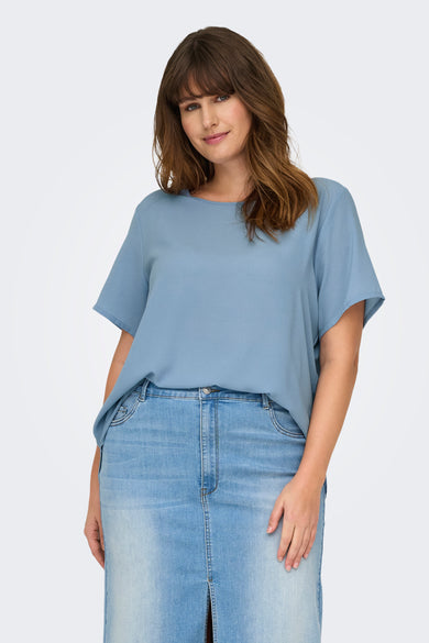 Blauw T-shirt met korte mouwen van CARMAKOMA, gedragen met een spijkerrok met split en witte sneakers.