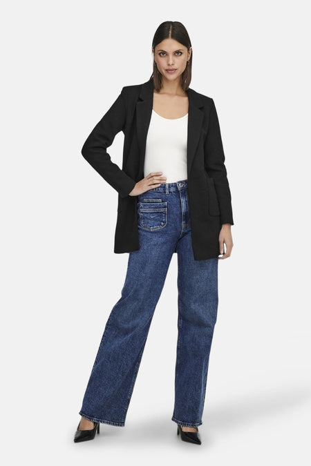 Blazer noir de ONLY, porté sur un débardeur blanc et un jean bleu à jambes larges.
