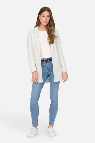 Blazer beige de ONLY, porté sur un pull et un jean avec une ceinture marron.