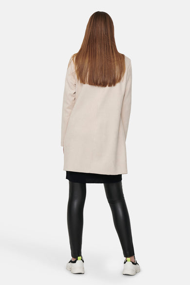 Veste longue beige de ONLY, avec des leggings noirs brillants et des baskets blanches.