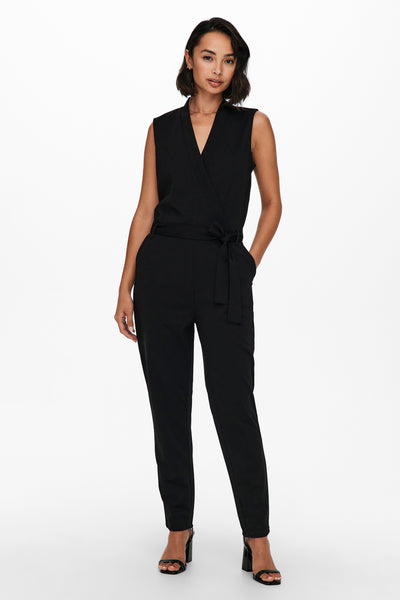 Combinaison noire de JDY, avec ceinture nouée et jambes fuselées, portée avec des talons hauts noirs.