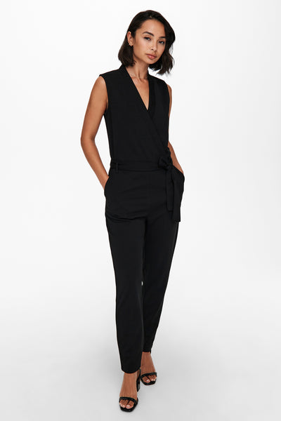 Combinaison noire par JDY, avec ceinture nouée, poches latérales et sandales noires à brides.

