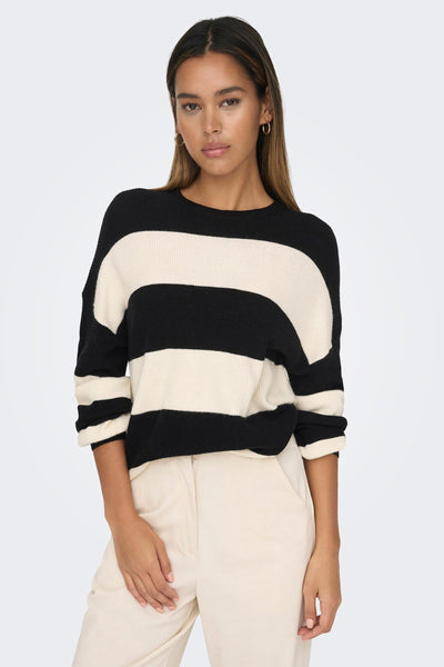 Pull col O noir de ONLY, à rayures horizontales blanches et porté avec un pantalon beige.
