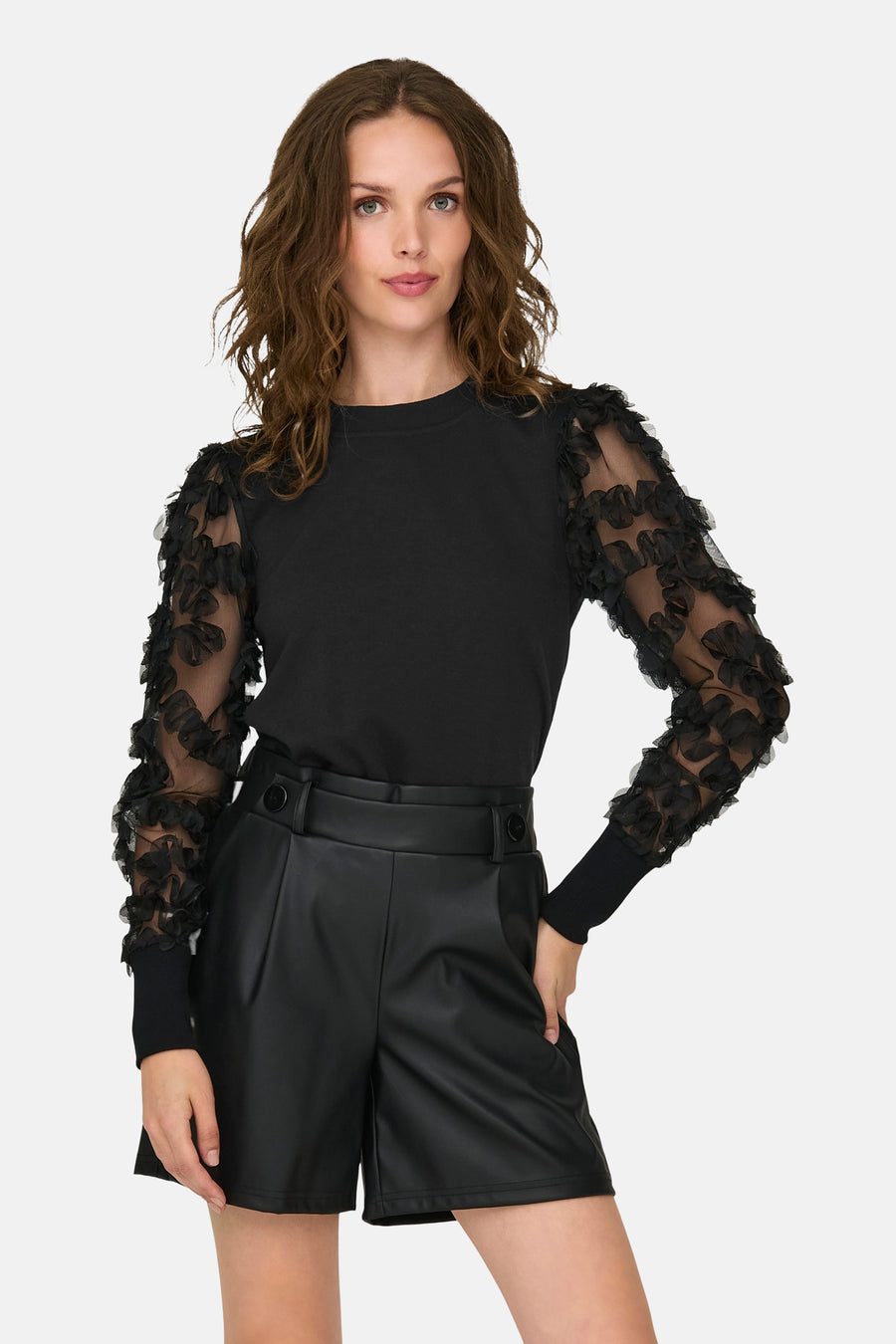 Sweat noir à col rond by JDY, avec manches longues en tulle ornées de motifs floraux, porté avec un short noir taille haute.

