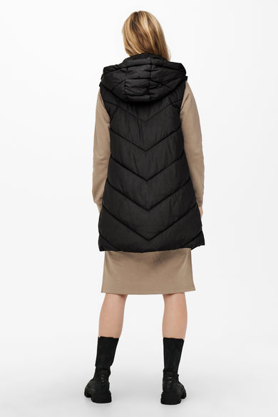 Bodywarmer noir JDY avec capuche, porté sur une robe beige et des bottes noires.