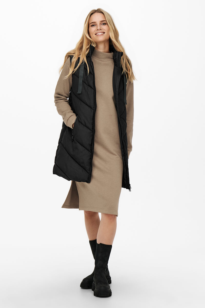 Bodywarmer noir de JDY, porté sur une robe et des bottes à semelle épaisse.
