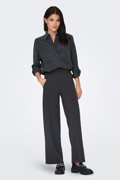 Pantalon de costume gris de JDY, coupe large, avec des poches et des chaussures noires à semelles épaisses.
