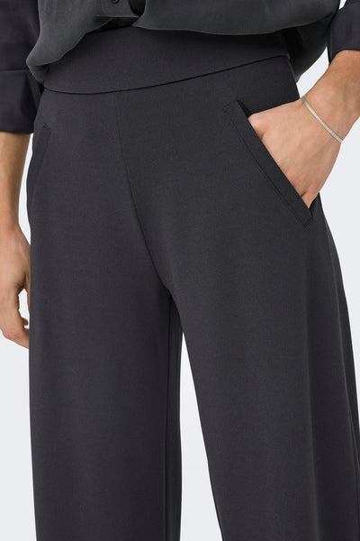 Pantalon de costume gris par JDY, avec une main dans la poche et un bracelet argenté.
