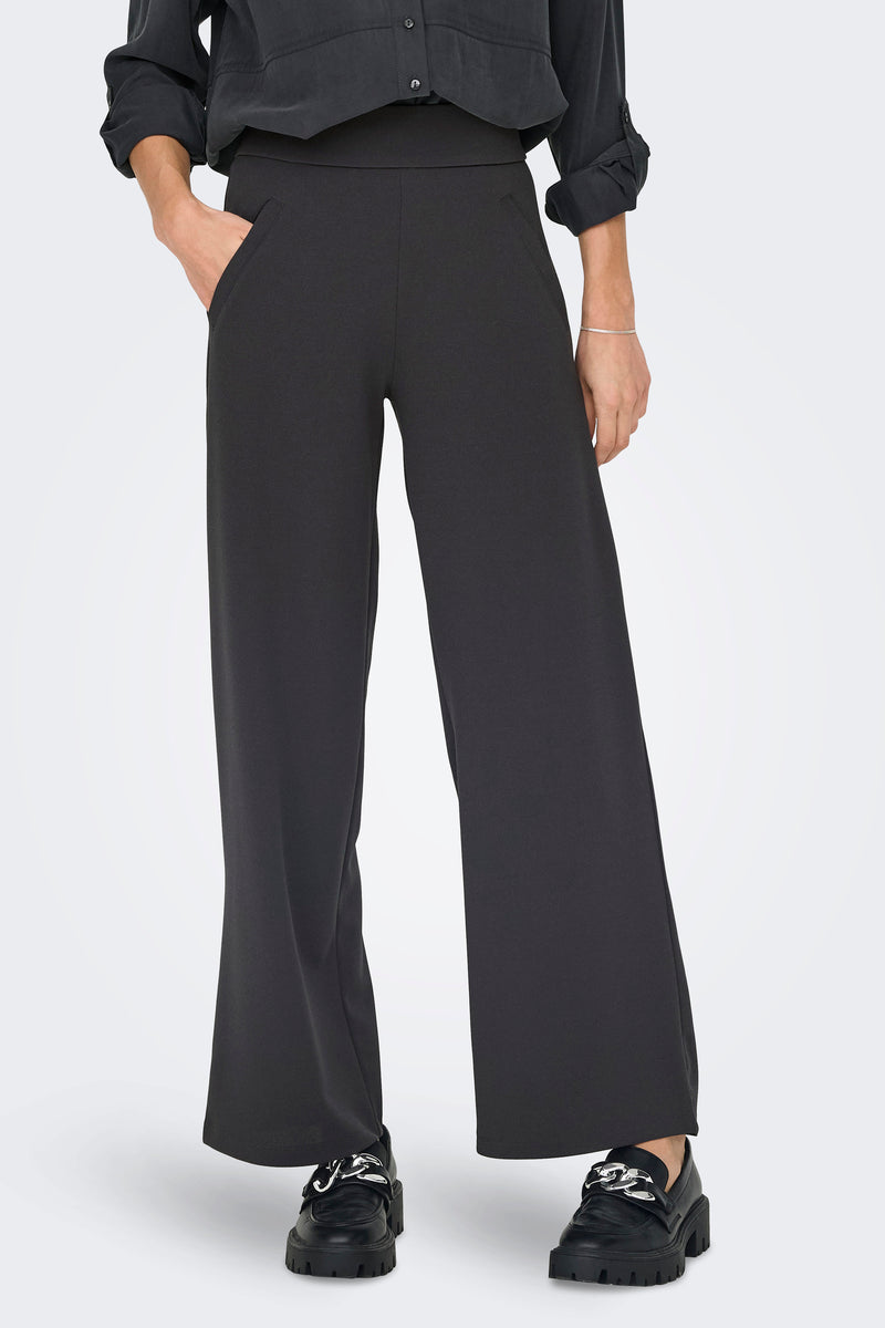 Pantalon de costume gris par JDY, coupe ample et jambes larges, porté avec des mocassins à plateforme.
