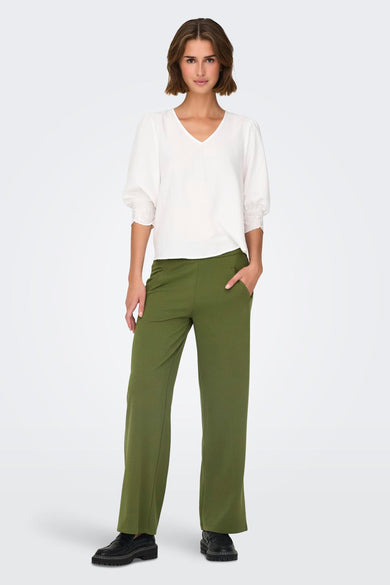 Pantalon de costume kaki de JDY, coupe droite, porté avec un chemisier blanc à manches courtes.
