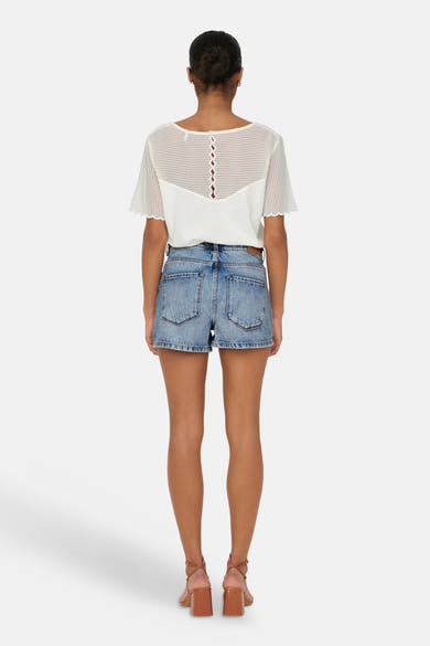 Short en jean bleu moyen de ONLY®, vue de dos, porté avec un haut blanc texturé et des sandales marron à talon carré.