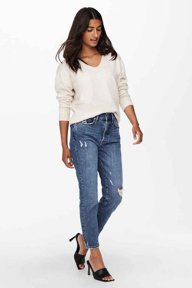 Pull à col en V écru de ONLY®, porté avec un jean bleu délavé et des mules noires à talons.
