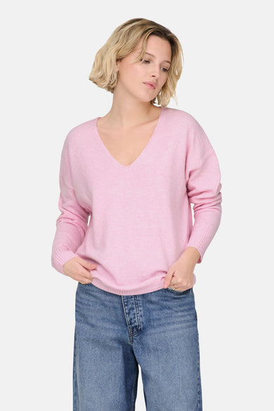 Pull rose à col en V de ONLY, porté avec un jean en denim bleu.