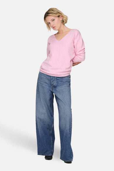 Pull à col en V rose de ONLY, porté avec un jean ample bleu.