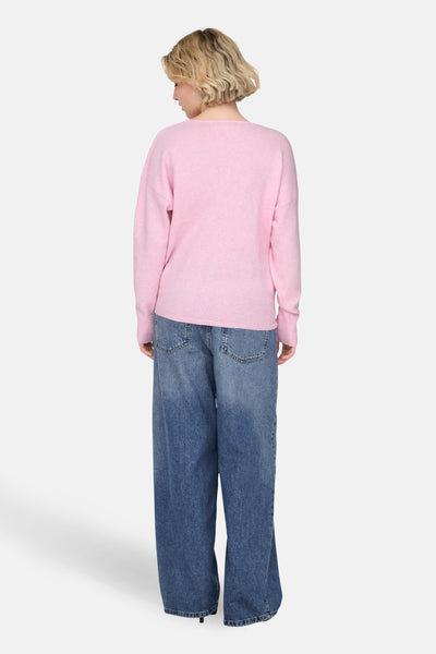 Pull à col en V rose de ONLY, porté avec un jean ample bleu.